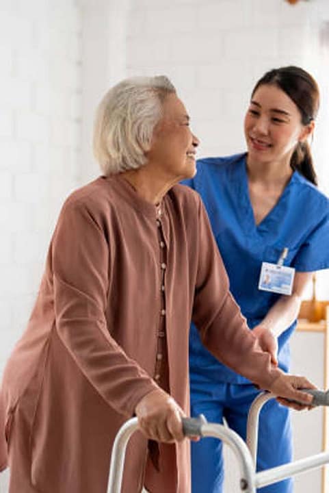 Asian senior older woman patient doing physical therapy with caregiver. Attractive specialist carer women help and support elder mature female practice walking slowly with walker at nursing home care.